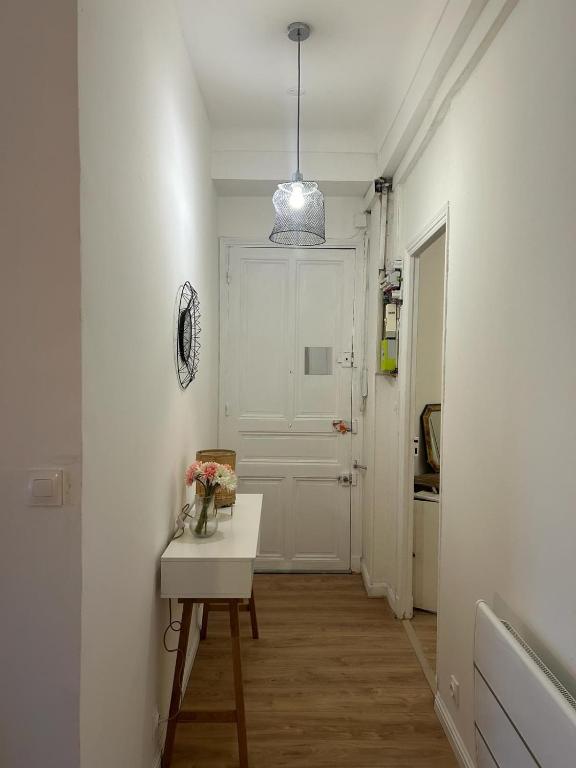 un couloir avec une table et une porte blanche dans l'établissement Le Gambetta, à Nice