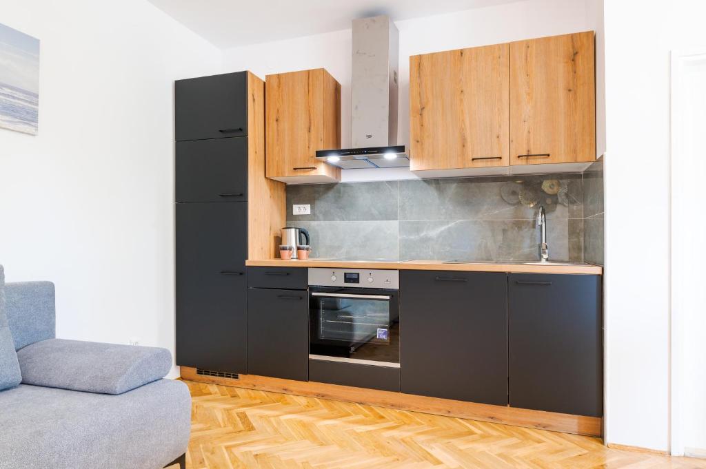 - une cuisine avec des appareils noirs et des armoires en bois dans l'établissement Apartment Goreta, à Kaštela