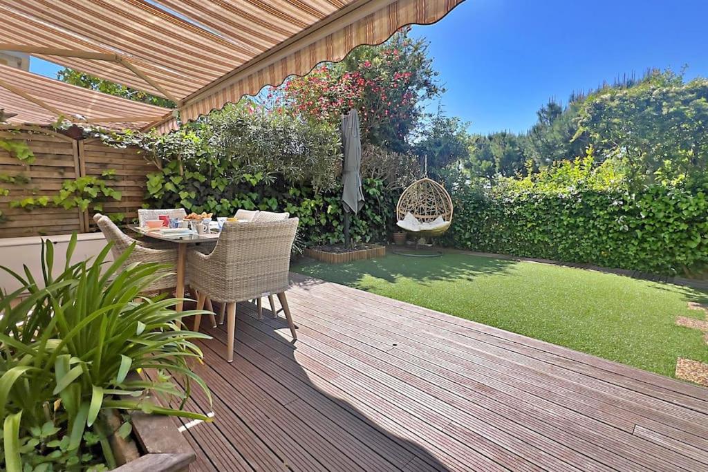 une terrasse en bois avec une table et des chaises. dans l'établissement The Flower Garden, à Nice