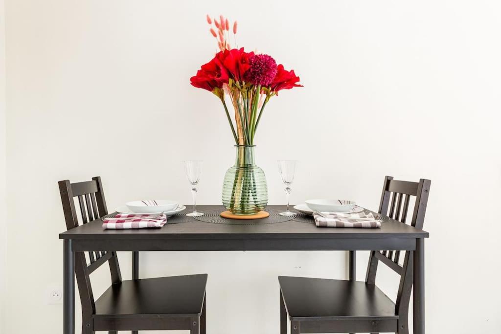 einen Tisch mit einer Vase mit roten Blumen darin in der Unterkunft studio lumineux in Choisy-le-Roi