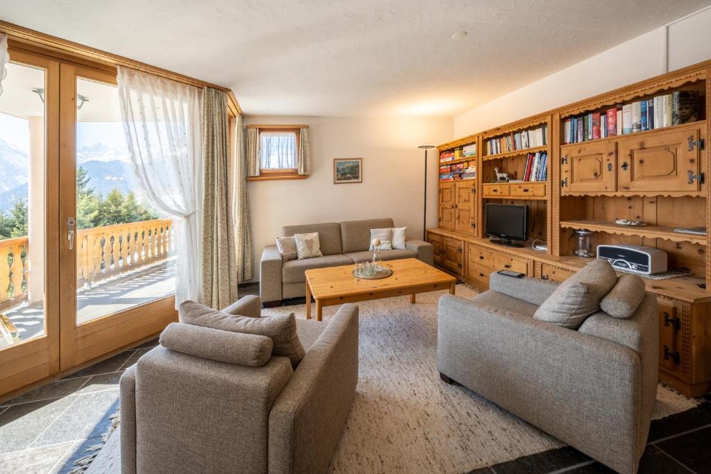 a living room with couches and a tv and a table at Chasa Munt Plan in Scuol