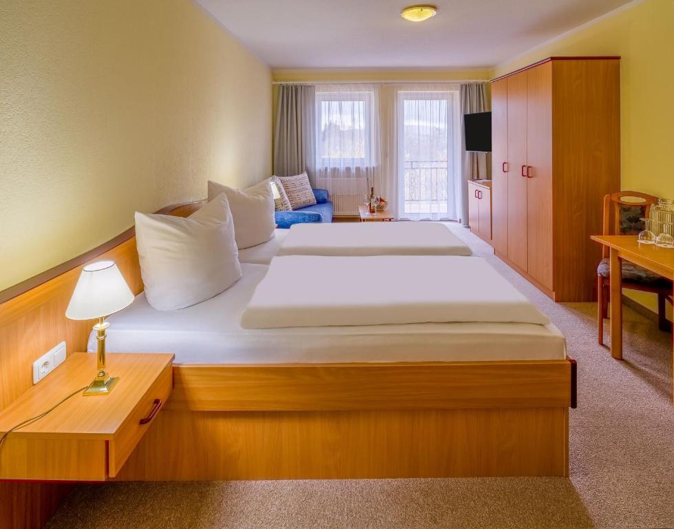 リントベルクにあるHotel Riesberghofの大きなベッドとデスクが備わるホテルルームです。