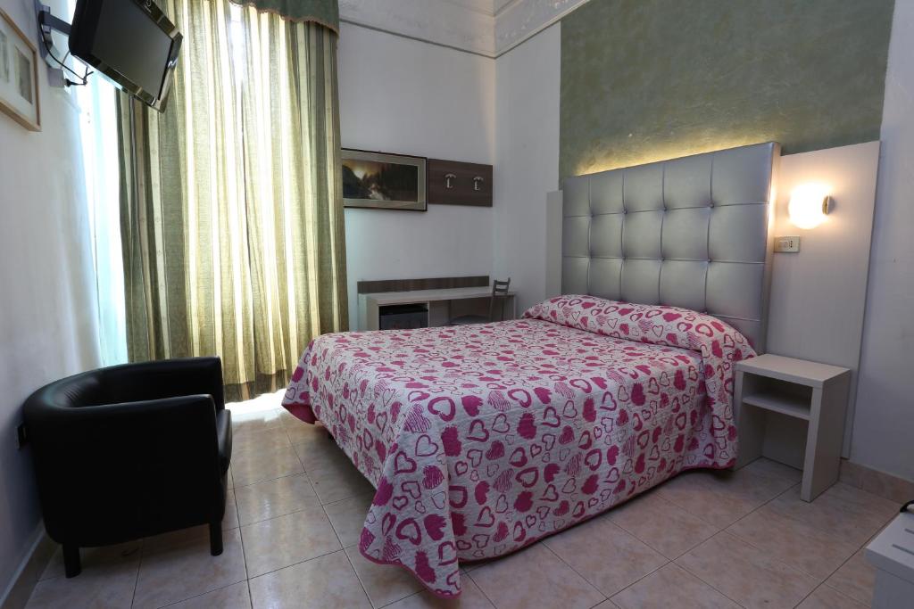 una camera con letto rosa e sedia di Hotel Piola a Milano