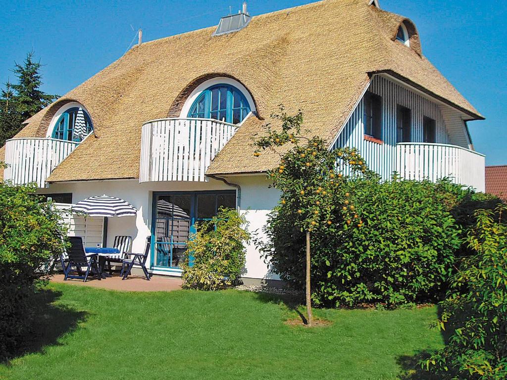 una casa con techo de gambrel con mesa y sillas en Im Schilf, en Wieck