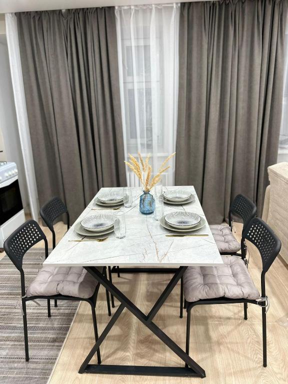 une table à manger avec des chaises, une table blanche et des chaises dans l'établissement 1 комнатная квартира, Уральск, à Uralsk