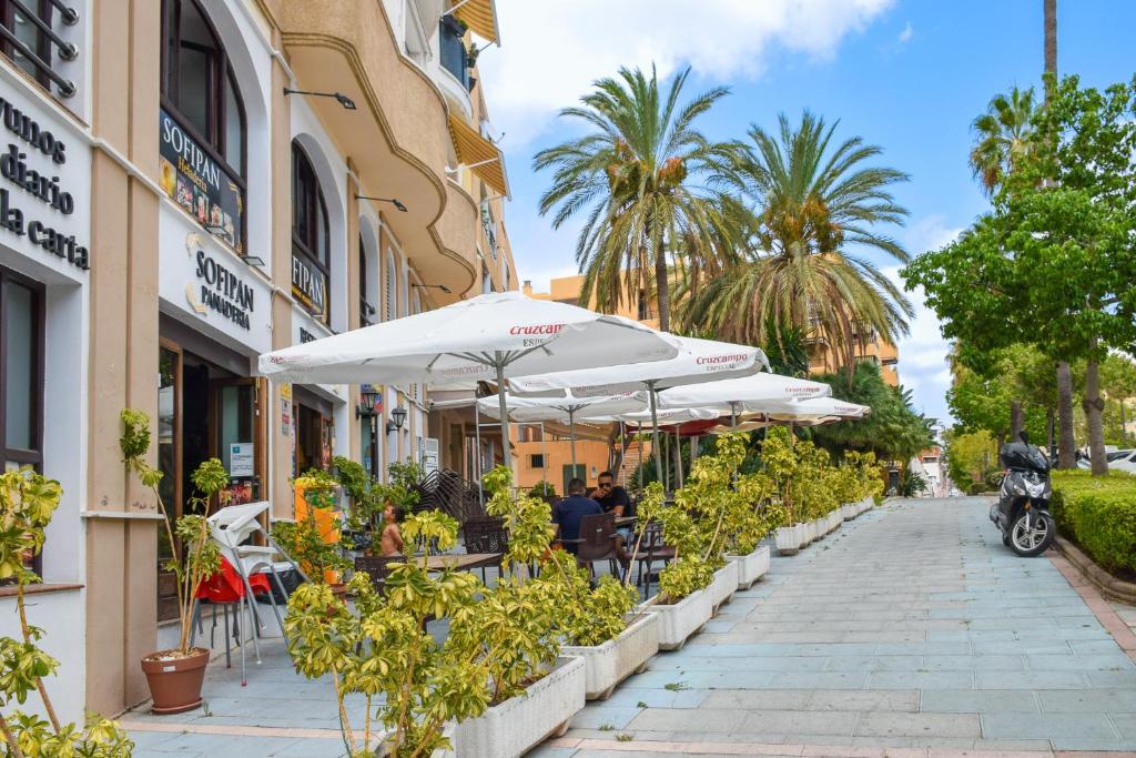 a sidewalk with white umbrellas and tables and plants at ESPECTACULAR PISO EN EL CORAZON DE MARBELLA in Marbella