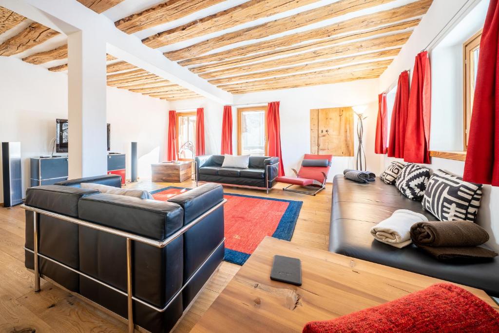 a living room with leather furniture and red curtains at Chasa Curtin 17 in Sent