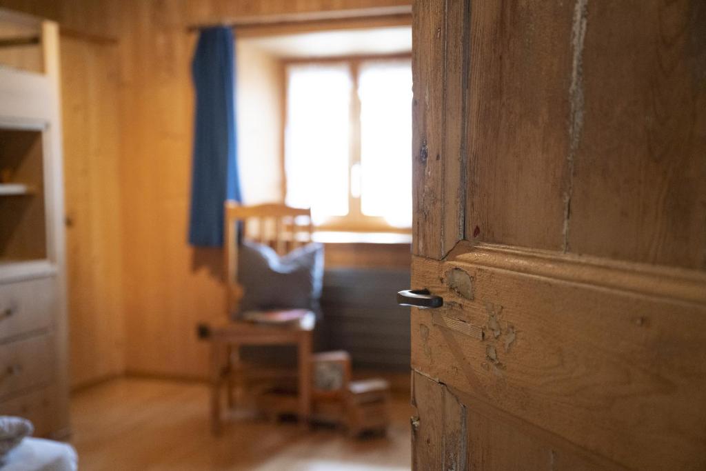una puerta abierta a una habitación con una silla y una ventana en Chasa Riatsch, en Ardez
