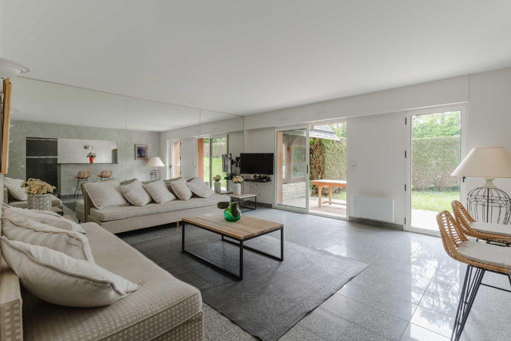 a living room with a couch and a table at Luxury haven with swimming pool and tennis court Deauville in Deauville