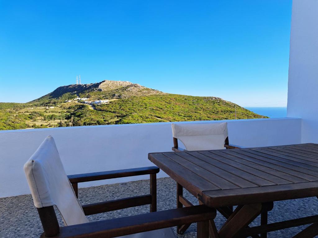 a wooden table and chairs on a balcony with a mountain at Sophie's Pourko House in Kýthira