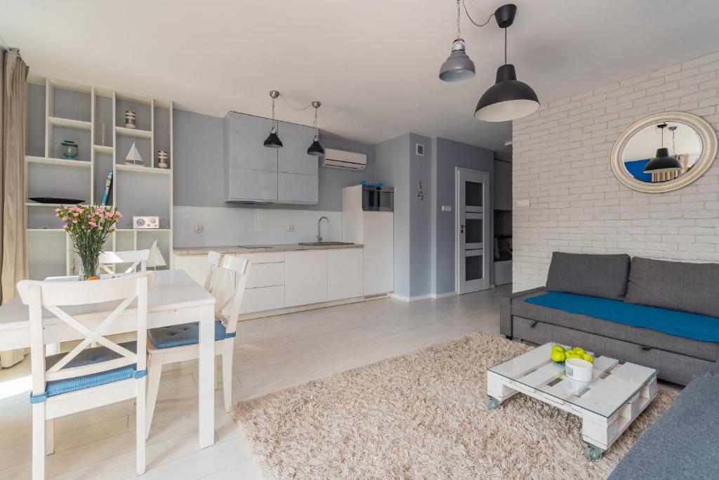 uma sala de estar e cozinha com um sofá e uma mesa em Apartamenty NCNK Baltic Park PREMIUM w Stegnie - 500 m do plaży em Stegna