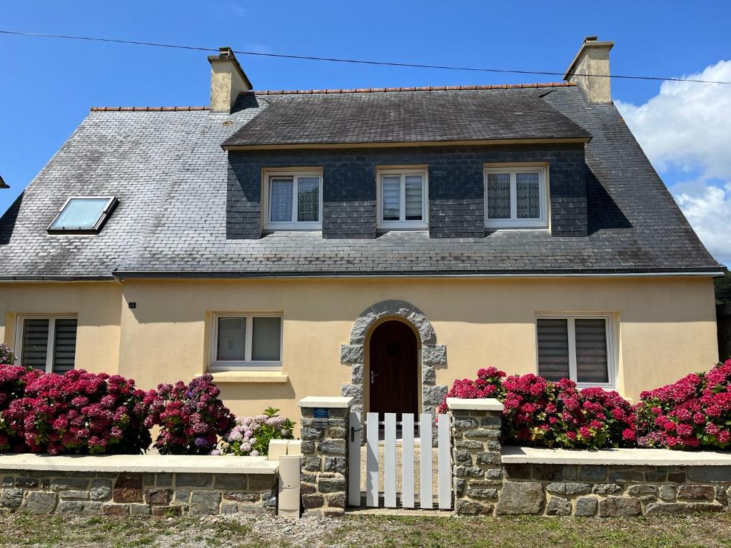 une maison avec une clôture blanche et des fleurs roses dans l'établissement Ty-magritt, à Saint-Nic