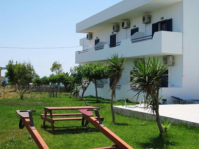 two benches in the grass in front of a building at Flisvos Apartments in Frangokastello