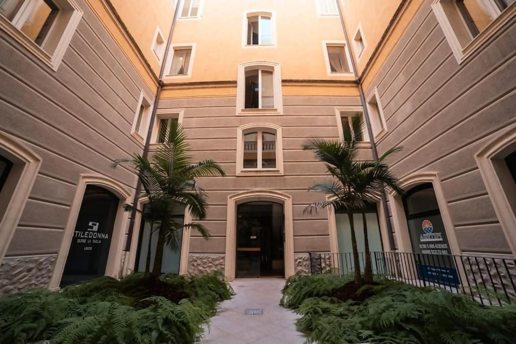 a building with two palm trees in front of it at Davids Room Palazzo Tamborino in Lecce