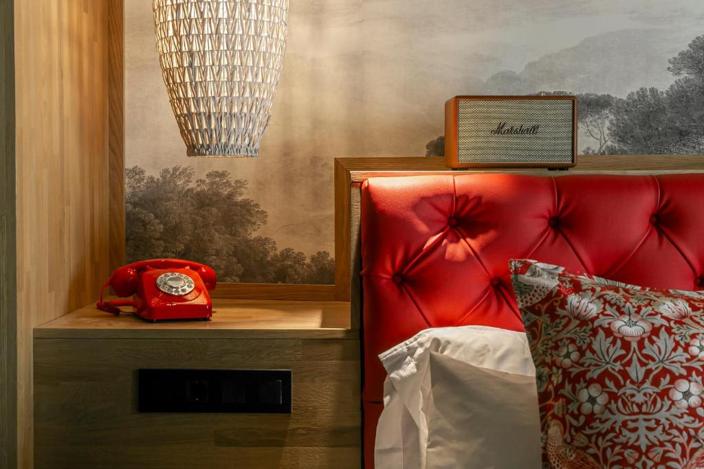 a bed with a red head board and a red phone at Hotel La Pau in Barcelona