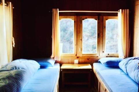 two beds in a room with two windows at Hotel waterfall,Benkar in Phakding