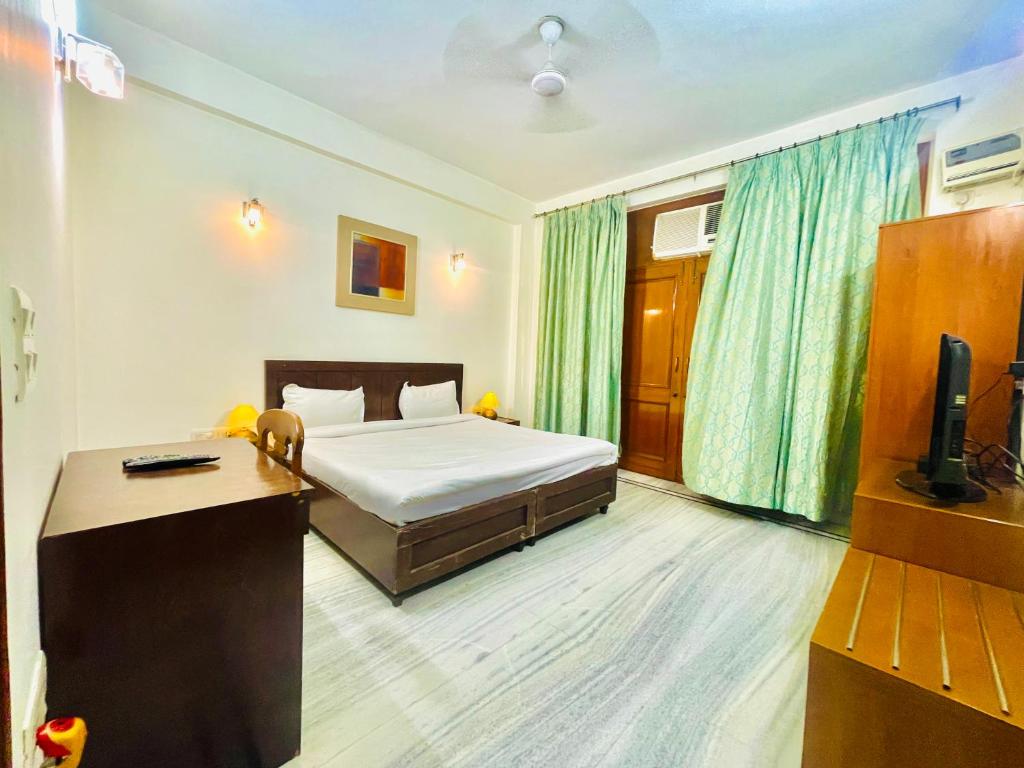 een slaapkamer met een bed, een bureau en een televisie bij BedChambers Service Apartment, South City 1 in Gurgaon