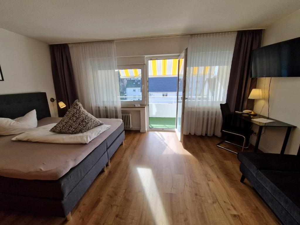 Schlafzimmer mit einem Bett, einem Schreibtisch und einem Balkon in der Unterkunft Apart Hotel Freiburg in Freiburg im Breisgau