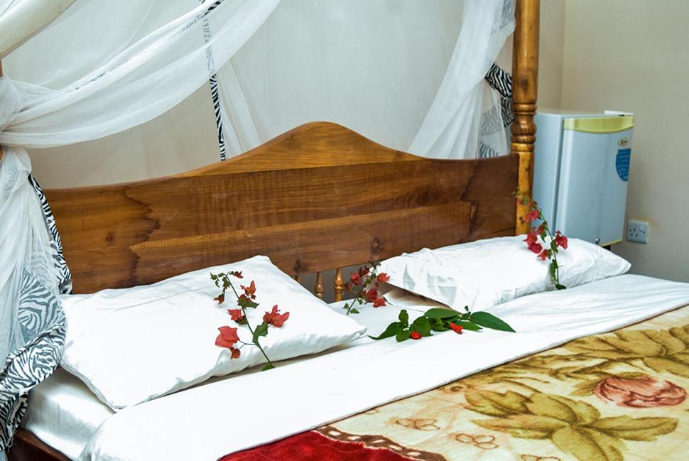 two beds with white sheets and flowers on them at KLH REST HOUSE in Karatu