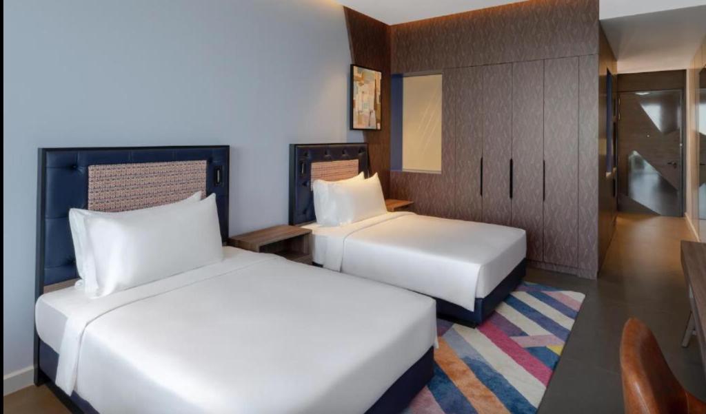 a hotel room with two beds and a table at Hyatt Centric Jumeirah - Dubai Twin Room - UAE in Dubai