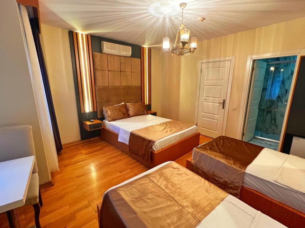 Cette chambre comprend 3 lits et un lustre. dans l'établissement Taksim Cetinkaya Suite, à Istanbul
