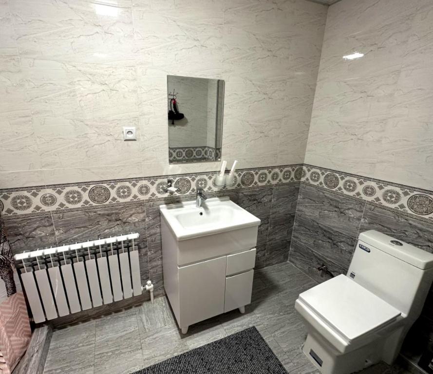 La salle de bains est pourvue de toilettes, d'un lavabo et d'un miroir. dans l'établissement Suzani National House, à Boukhara