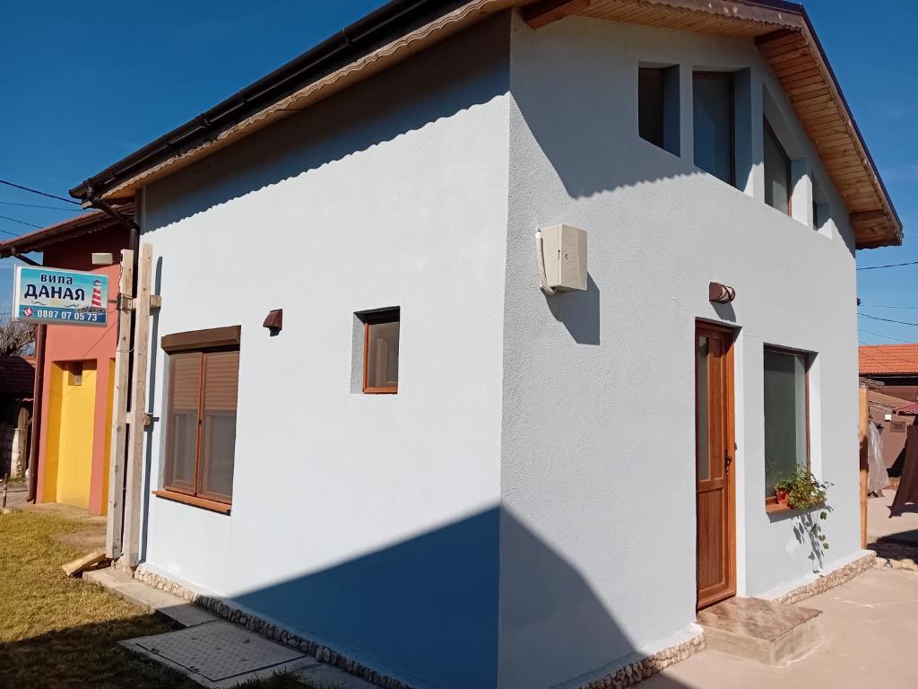 ein weißes Haus mit einer blau-weißen Fassade in der Unterkunft Вила за гости Даная-Фар Шабла in Tyulenovo