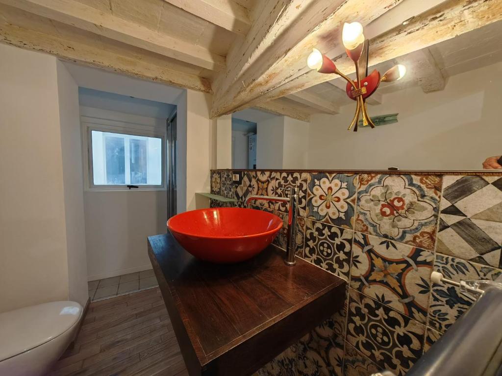 un bagno con una ciotola rossa su un bancone in legno di Jolie Maison au coeur de Parma avec Parking privé inclusif a Parma