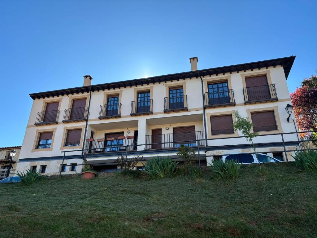 a large white building with balconies on a hill at Apartamento Mirador del Pantano 1 in Vinuesa