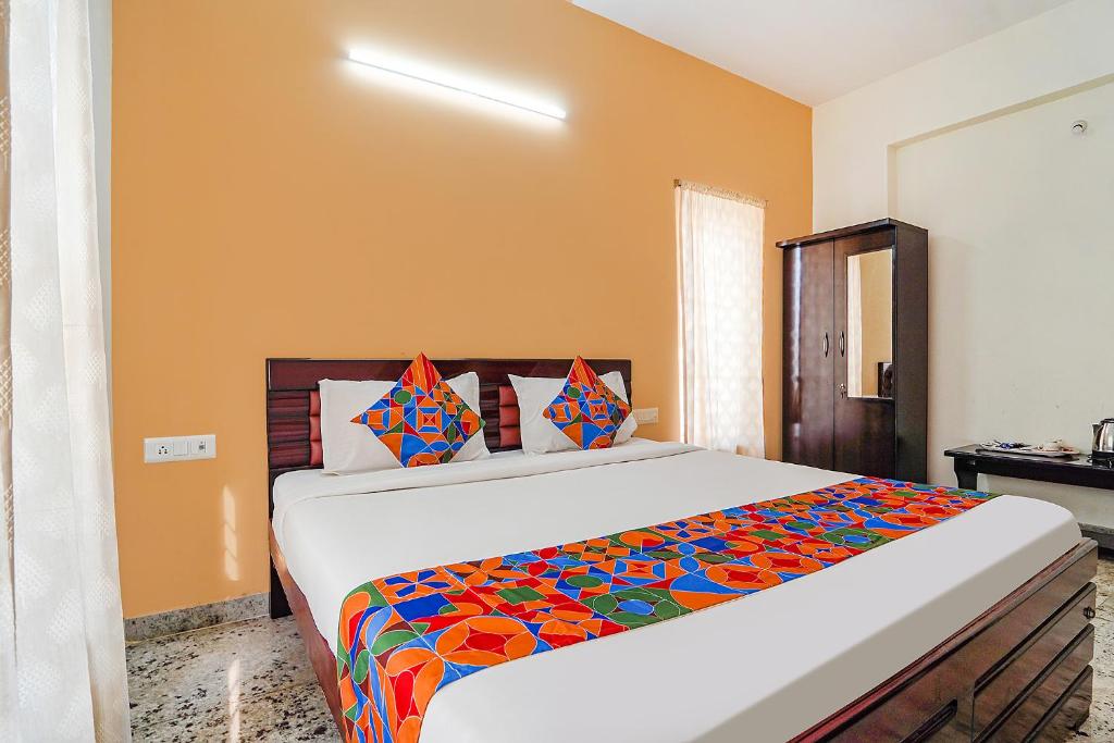 1 dormitorio con 1 cama grande con una manta colorida en FabHotel S V Homestay Tirupati, en Tirupati