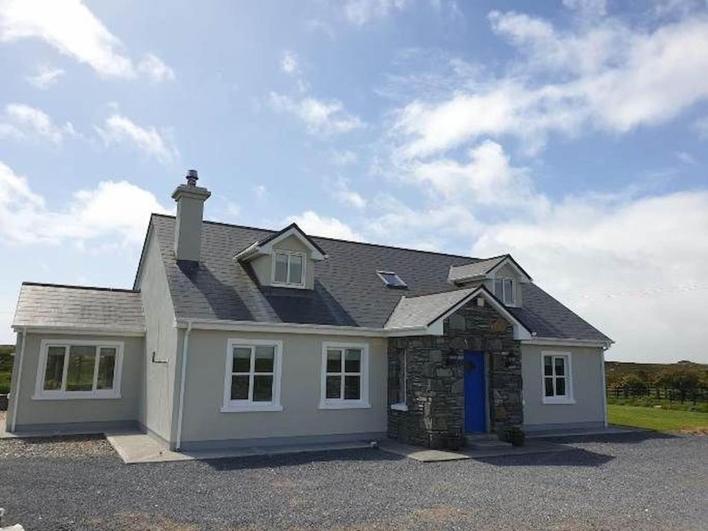 a large white house with a blue door at Hillside House in Ballinaboy