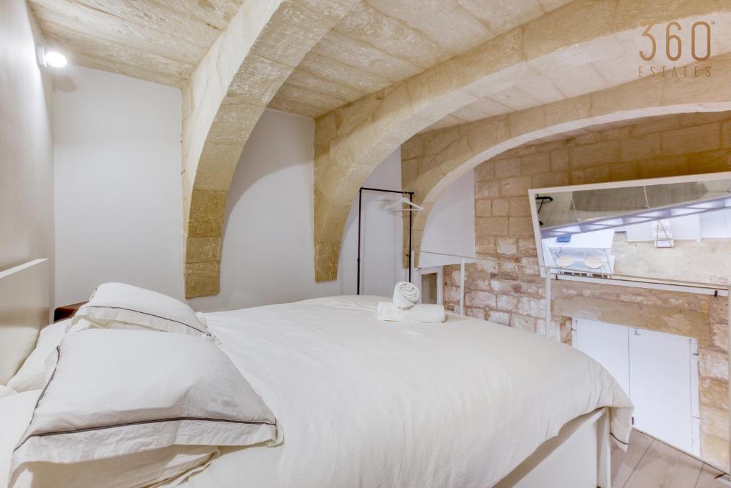 1 dormitorio con cama blanca y pared de piedra en Authentic & cosy duplex home in charming Rabat By 360 Estates, en Rabat