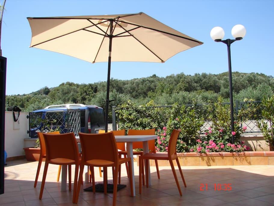 uma mesa e cadeiras com um guarda-sol num pátio em Casa Albertina em Castro di Lecce