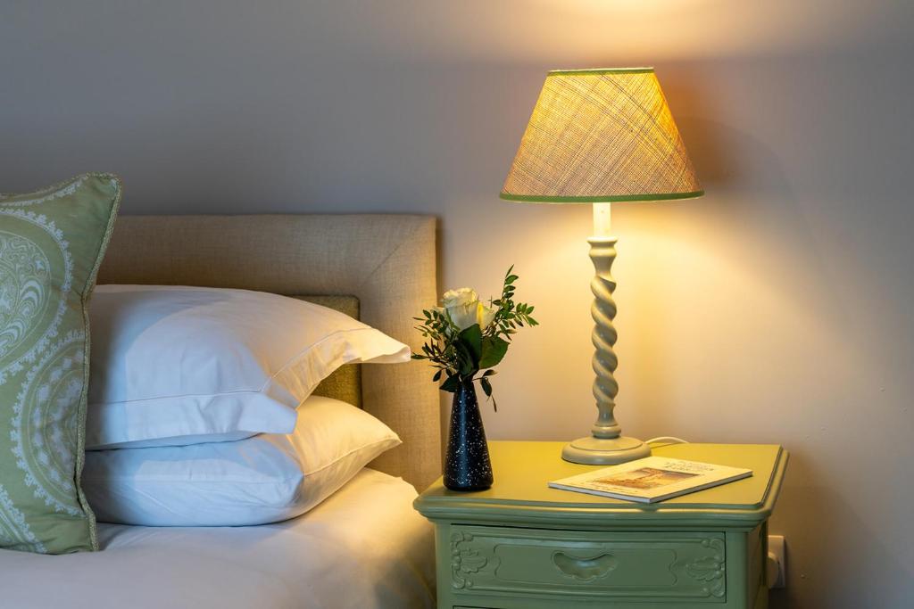 a lamp on a night stand next to a bed at Queen's Cottage Barrowford in Barrowford