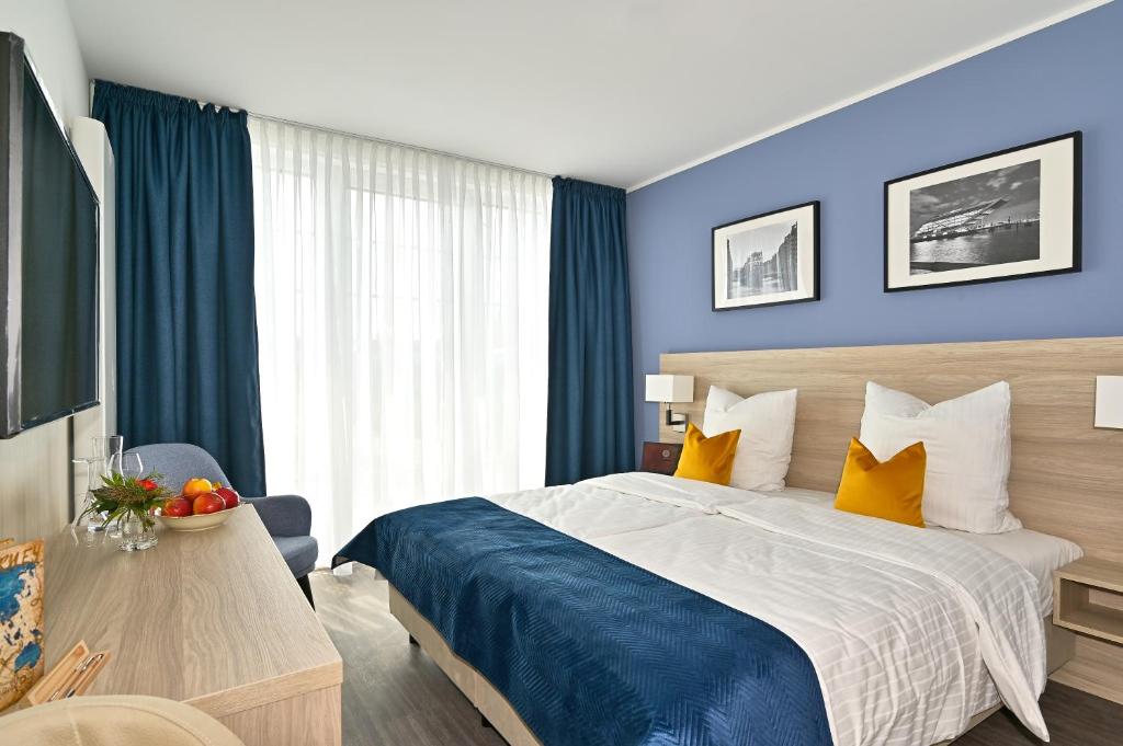 a bedroom with a large bed with blue walls and yellow pillows at HotelHafenWedel in Wedel