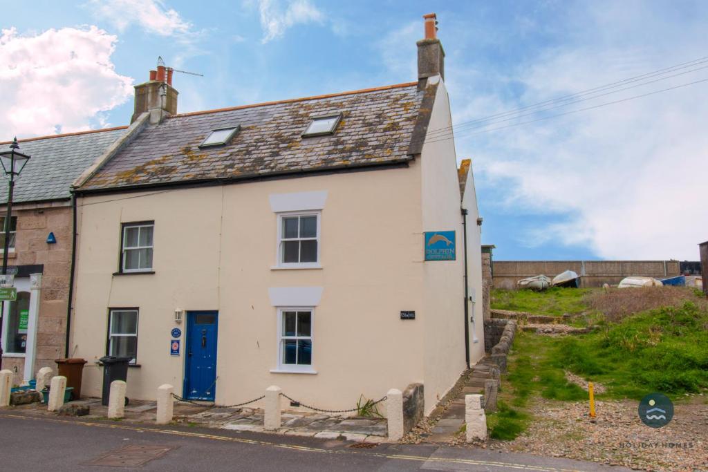 an old white house with a blue door at Dolphin Cottage Chesil Beach in Portland