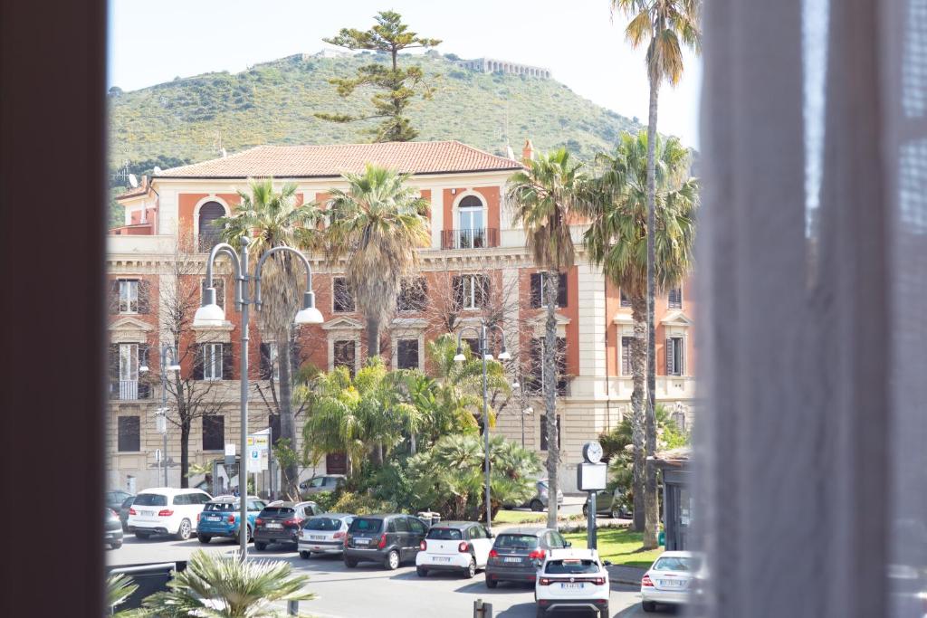a building with cars parked on a street with palm trees at Affittacamere Piazza Mazzini in Terracina