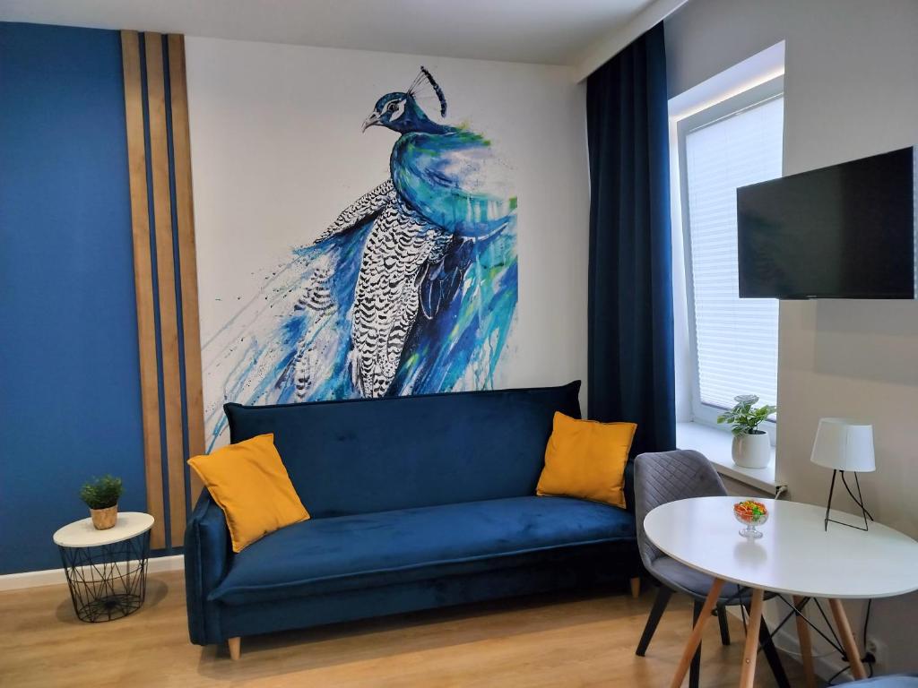 eine blaue Couch in einem Wohnzimmer mit einem Gemälde an der Wand in der Unterkunft STUDIO BLUE BIRD PIĘKNA 2 wejście na kod CENTRUM in Pabianice