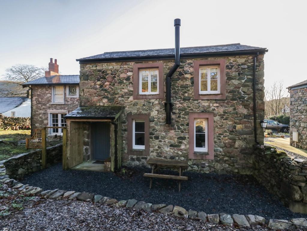 a stone house with a bench in front of it at Church How Cottage in Seascale