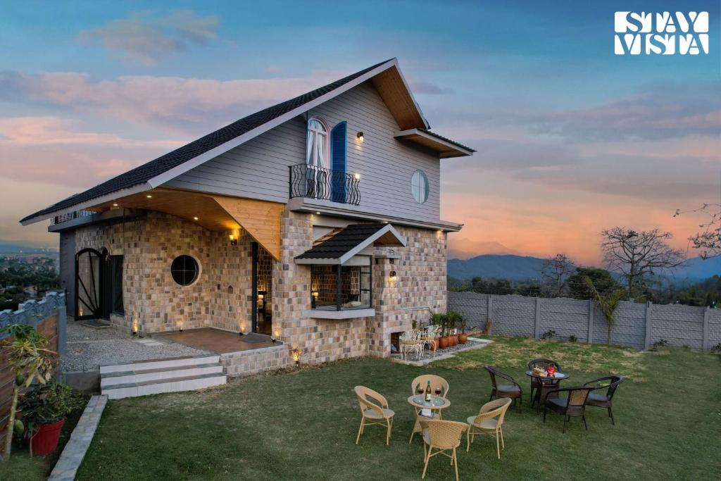 una casa en una colina con sillas y una mesa en StayVista at Ivycrest Estate, en Dehradun