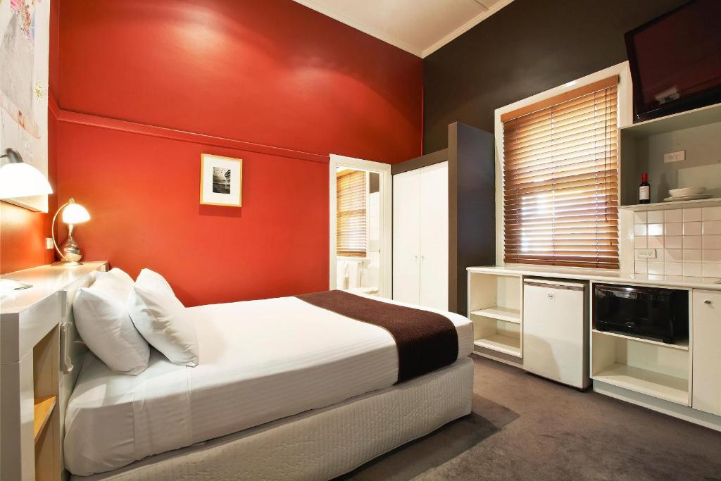 1 dormitorio rojo con 1 cama y lavamanos en Tolarno Hotel - Balazac Room - Australia en Melbourne