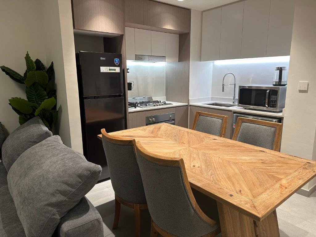 a kitchen with a wooden table and a refrigerator at WelcomeHome Apartments Aljada in Sharjah