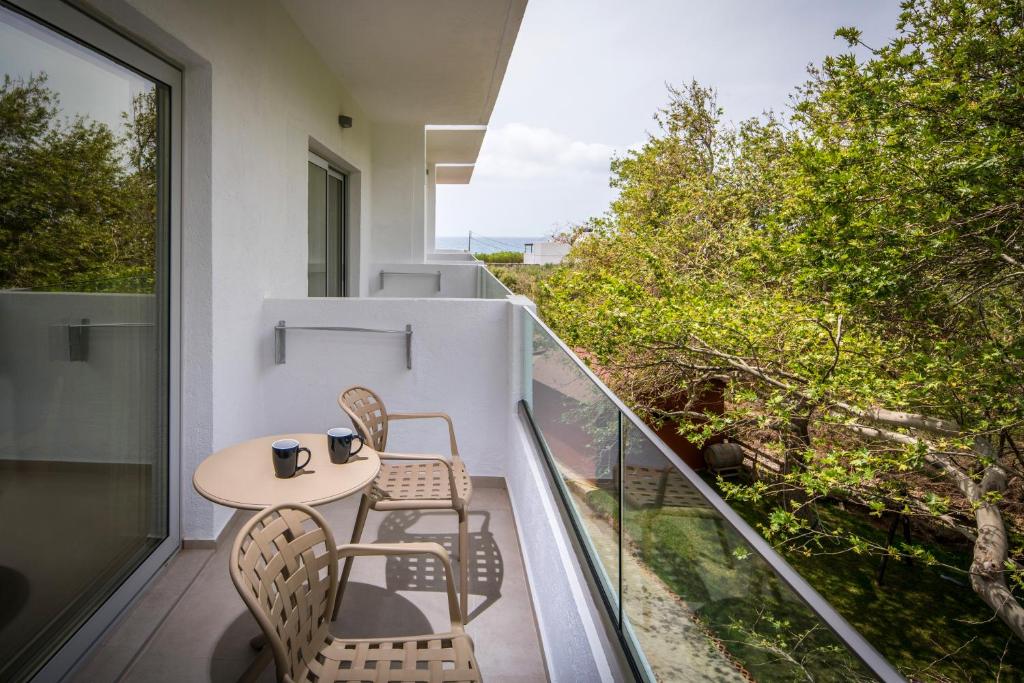 a balcony with two chairs and a table on a balcony at South Coast Hotel in Makry Gialos
