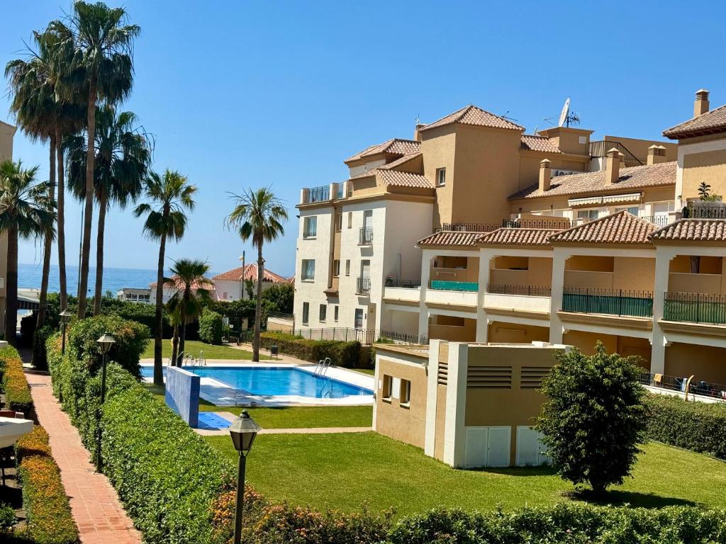 een groot appartementencomplex met een zwembad en palmbomen bij Strandnära boende i Torrox Costa in Torrox Costa