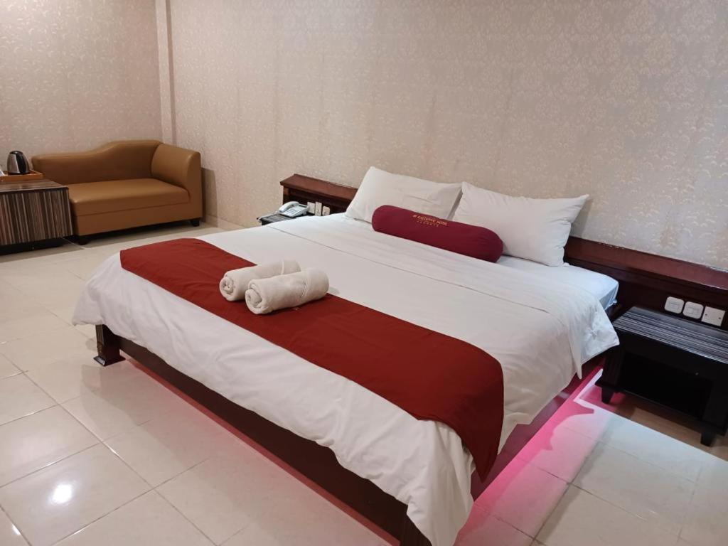 Schlafzimmer mit einem großen Bett mit roter und weißer Bettwäsche in der Unterkunft 3PUTRA HOTEL JAKARTA in Jakarta
