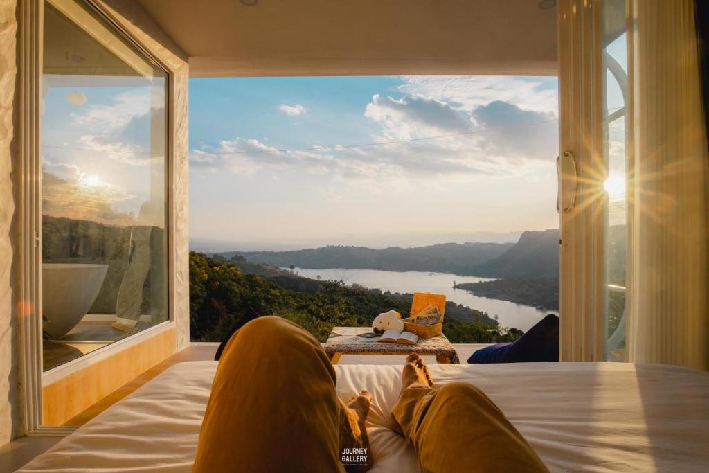 una persona sdraiata su un letto che guarda fuori da una finestra di Make me see cloud - Chiang rai a Mae Suai