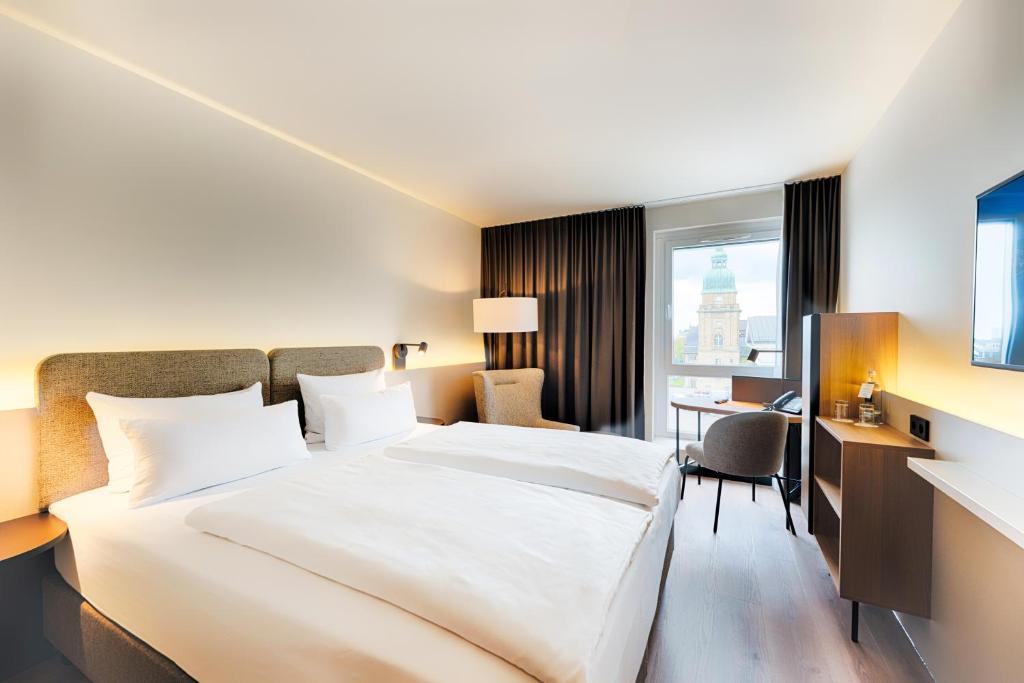 ダルムシュタットにあるWelcome Hotel Darmstadt City Centerの大きなベッドとデスクが備わるホテルルームです。