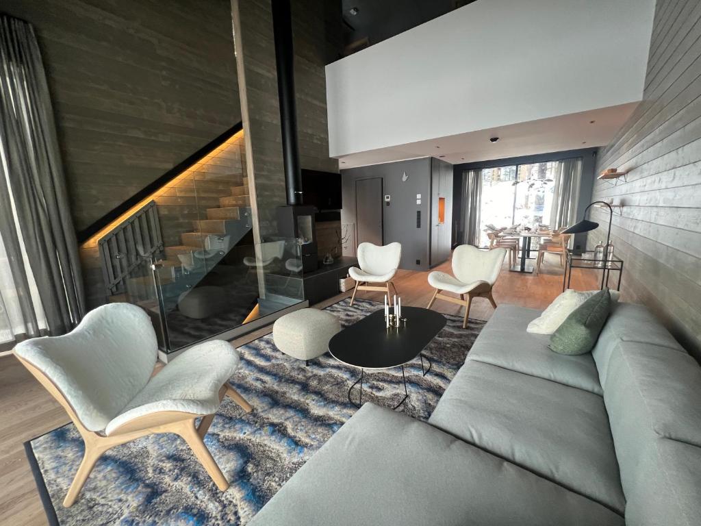 a living room with a couch and chairs and a staircase at Snowbird Villas (Arctic Nook) in Kittilä