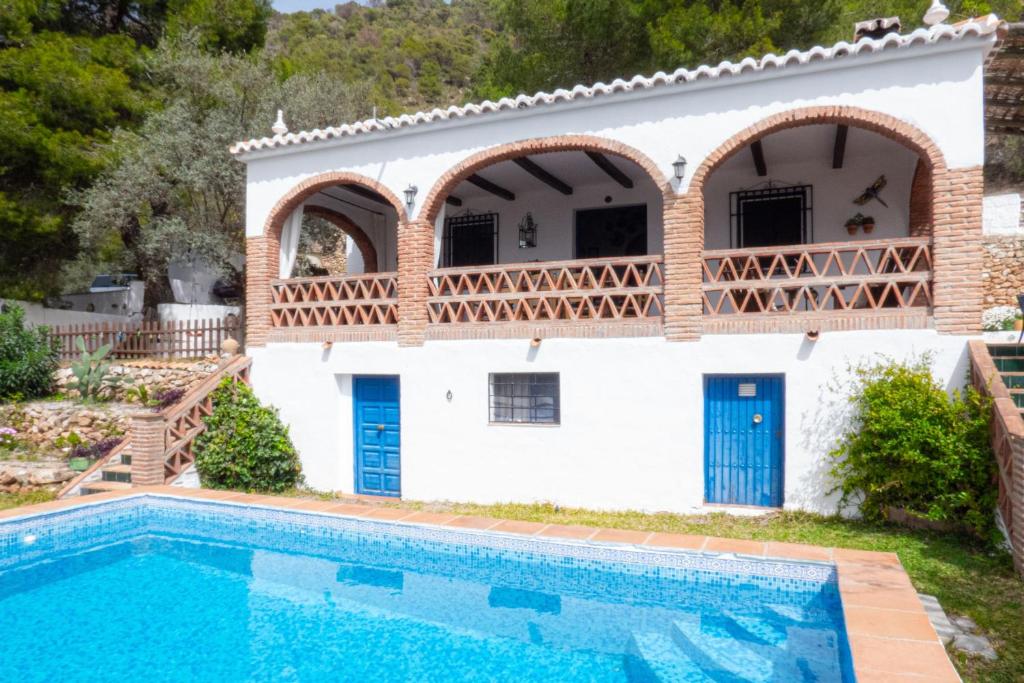 a villa with a swimming pool in front of a house at Cortijo Fernando in Frigiliana