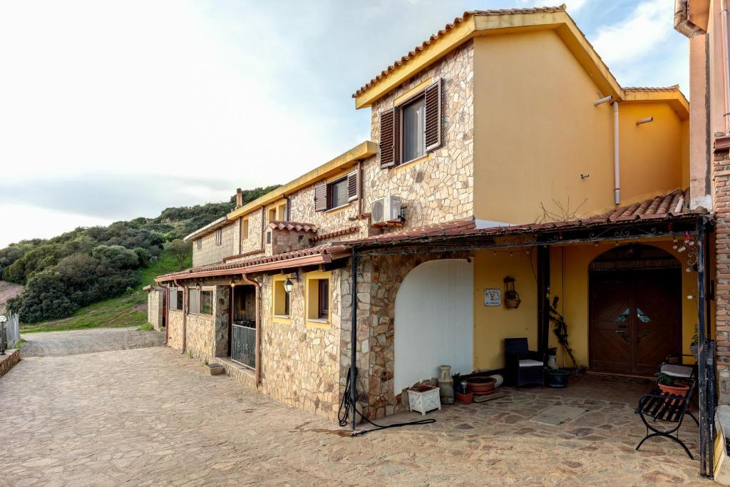 a stone house with a garage on a street at L'Aquila in Arbus